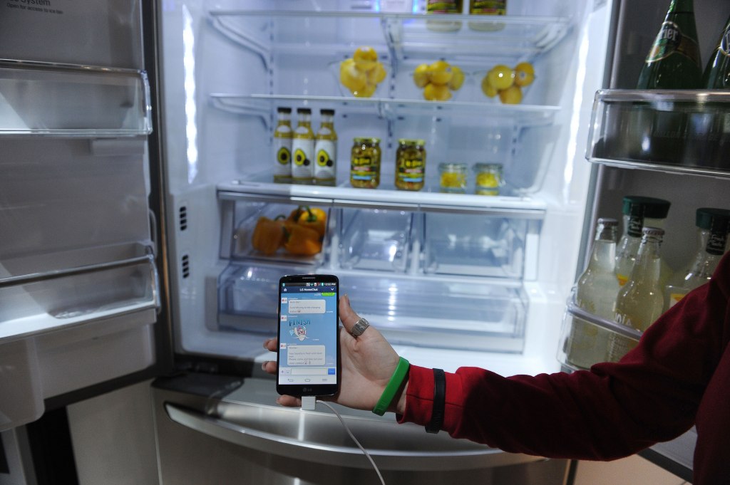 A LG representative shows a smartphone with Home Chat in front of a LG smart refrigerator on the final day of the 2014 International CES, January 10, 2014 in Las Vegas, Nevada. The LG Smart Home system with the Home Chat smart platform allows users to communicate with home appliances via text message. AFP PHOTO / ROBYN BECK (Photo credit should read ROBYN BECK/AFP/Getty Images)